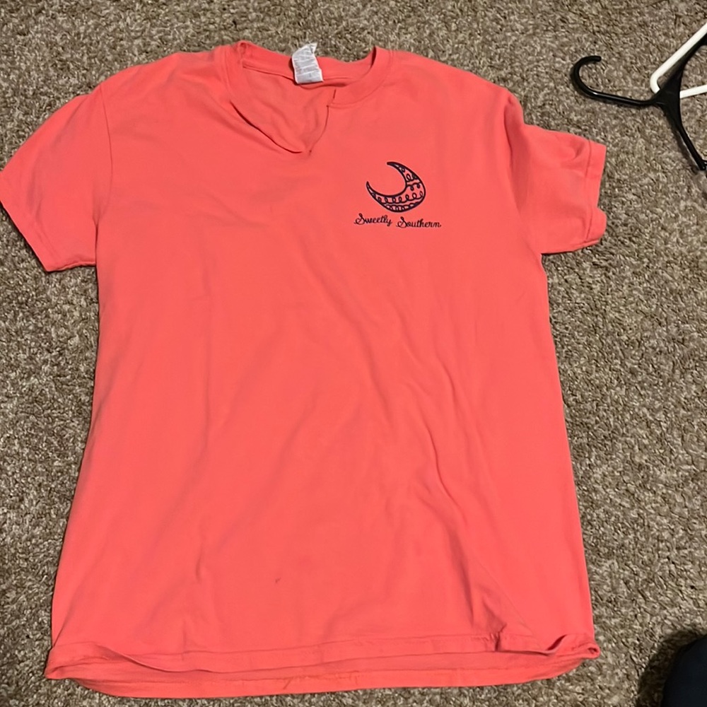 The shirt is a coral pink. The brand is sweetly southern.